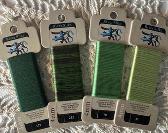 May include: Four spools of River Silks premium hand-dyed silk ribbon in shades of green. Each spool is 4mm wide and contains approximately 5-5.5 yards of ribbon. The spools are labelled with the colour number and "River Silks" logo.
