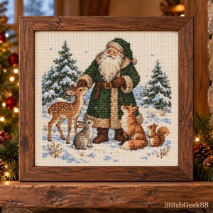 May include: A framed cross-stitch embroidery featuring Santa Claus in a dark green coat standing in a snowy forest with a deer, a rabbit, a fox, and a squirrel. The text StitchGeek88 is visible in the bottom right corner of the image.