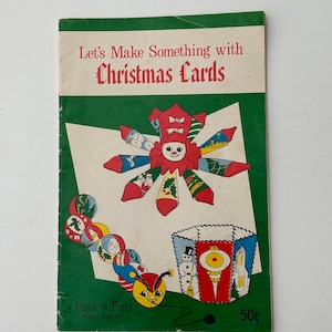 May include: A vintage book cover titled "Let's Make Something with Christmas Cards." The cover has a green border and illustrations of Christmas-themed crafts, including a paper doll and ornaments. The book is a Pack-o-Fun publication.