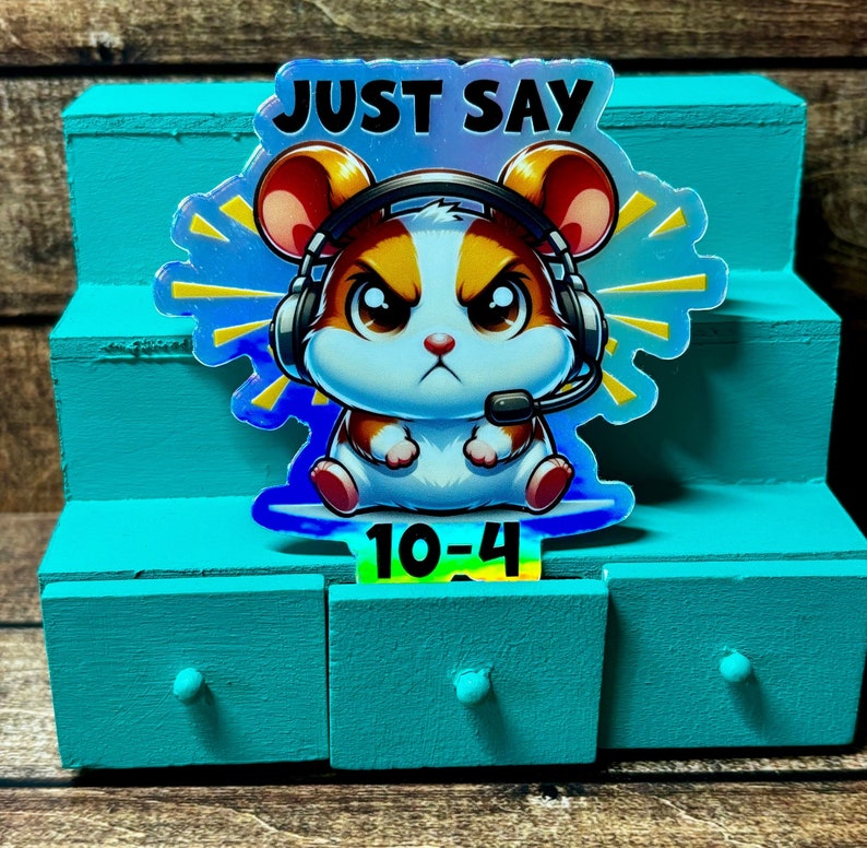 Pode incluir: Um adesivo hologr&aacute;fico com um hamster de desenho animado usando um fone de ouvido e dizendo "Just Say 10-4".