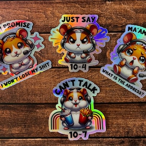 May include: Five holographic stickers featuring a cartoon hamster wearing headphones and a microphone. The stickers have different phrases, including "Today I Promise I Won't Lose My Shit", "Just Say 10-4", "Ma'am, Ma'am What Is The Address?", "Can't Talk 10-7".