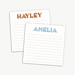 May include: Two lined notepads with names at the top. The top notepad has the name "HAYLEY" in orange text. The bottom notepad has the name "AMELIA" in blue text.