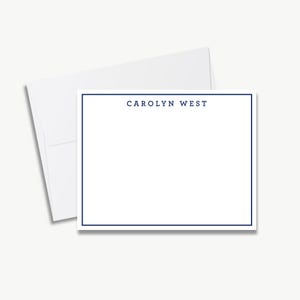 A blank white card with a blue border, placed on top of an envelope.