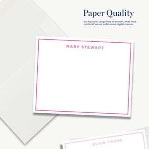 The image is a white card with a pink border, featuring the names "Mary Stewart" and "Blair Young" printed on it. The card is placed on a white background, and there is a white envelope in the background as well.