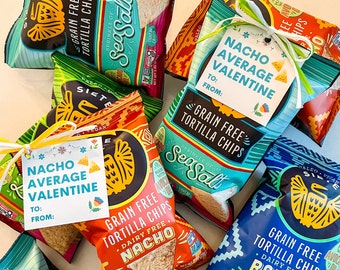 May include: A collection of six bags of grain-free tortilla chips, each with a different flavour. The bags are decorated with colourful designs and the text "Grain Free Tortilla Chips".  A small tag with the text "Nacho Average Valentine" is attached to one of the bags.