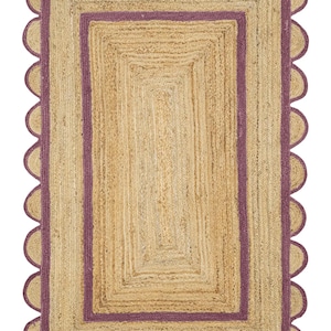 Puede incluir: Alfombra rectangular de yute con borde festoneado y borde morado. La alfombra tiene una textura natural tejida y un color marrón claro. El rectángulo interior tiene un color marrón más oscuro.