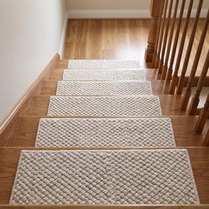Op de afbeelding: Een reeks rechthoekige beige traptreden met een verhoogd, noppig, getextureerd oppervlak. Elke trede is gecentreerd op een houten trede, met een consistente geweven constructie en afgewerkte randen die de breedte van de trap bedekken.