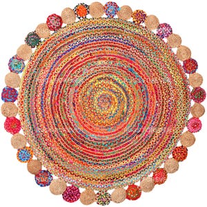 May include: Round jute rug with a multi-colored woven design and a fringe border of colorful pom-poms.