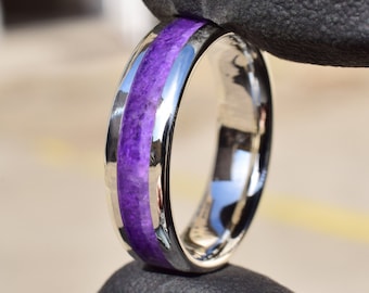 May include: A silver ring with a purple inlay. The ring is polished and has a smooth finish.
