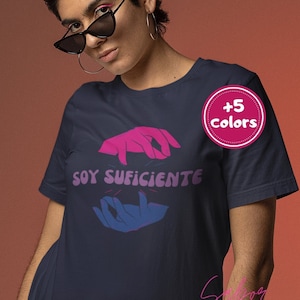 May include: Navy blue t-shirt with pink and blue hands and the text "SOY SUFICIENTE" in pink. The t-shirt has a +5 colors label.
