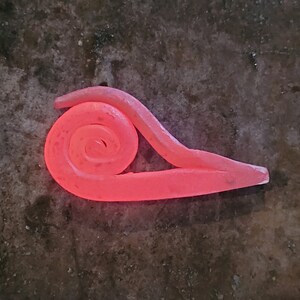 May include: A red-hot metal spiral, forged in a blacksmith's fire, is shaped into a unique design. The metal glows with a bright orange hue, highlighting the intricate details of the spiral.