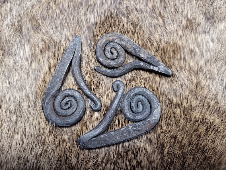 May include: Three metal spirals, each with a unique shape and design, are arranged in a triangular pattern on a brown furry surface.
