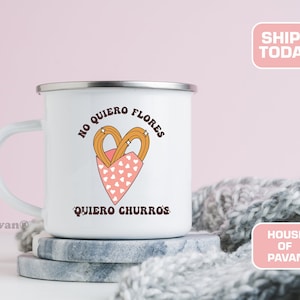 Op de afbeelding: Witte emaille mok met een roze hartontwerp en de tekst "No quiero flores, quiero churros".