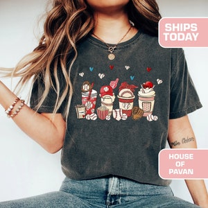 May include: A dark gray t-shirt with a graphic of baseball-themed cups, popcorn, and baseballs. The text "House of Pavan" is on the bottom right corner of the image.