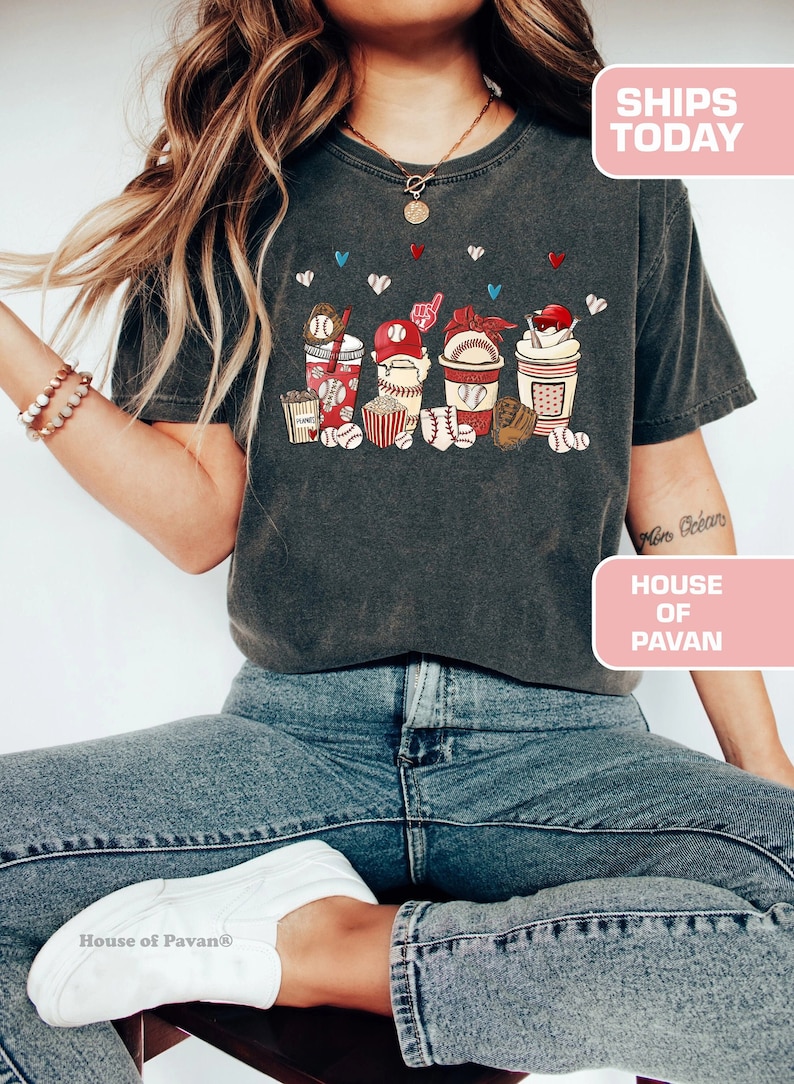 May include: A dark gray t-shirt with a graphic of baseball-themed cups, popcorn, and baseballs. The text "House of Pavan" is on the bottom right corner of the image.