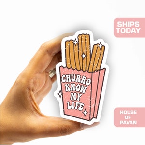 May include: A pink and white sticker with a cartoon illustration of a bag of churros. The bag has the text "Churro Know My Life" in a retro font.