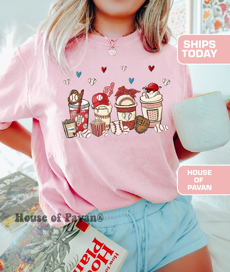 May include: Pink t-shirt with a graphic of baseball-themed drinks, popcorn, and baseballs. The graphic includes the words "PLANNER" and "HOME".