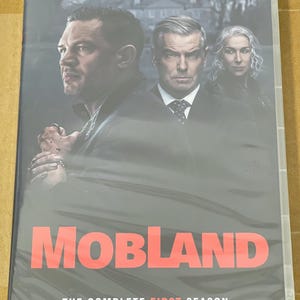 May include: DVD case for "MobLand: The Complete First Season." The cover shows three actors in dark clothing against a blurred backdrop. The title "MobLand" is in large, red letters, with the season details below.