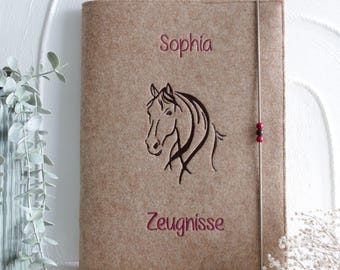 May include: A tan felt document folder featuring an embroidered dark brown horse head silhouette in the center. The name Sophia is embroidered in dark red above the horse, and the word Zeugnisse is embroidered in dark red below the horse.