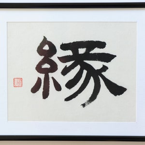 May include: Black ink calligraphy on white paper in a black frame. The calligraphy depicts the Japanese characters "永遠" which means "eternity".