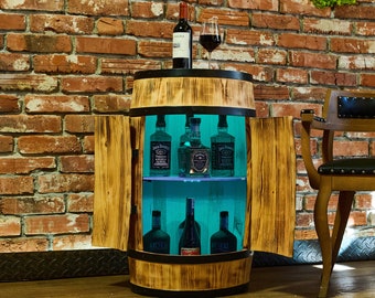 May include: A wooden barrel-shaped bar cabinet with two doors and a glass shelf. The cabinet has a dark brown stain and is lit with blue LED lights. The cabinet is filled with bottles of spirits.
