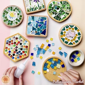 Puede incluir: Un conjunto de posavasos de mosaico en varias formas, incluyendo redondos, cuadrados, de corazón y hexagonales. Los posavasos presentan azulejos de vidrio de colores en marcos de madera. Algunos posavasos tienen elementos decorativos.
