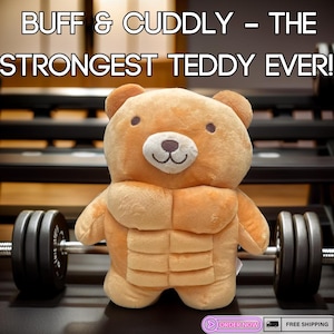 Peut inclure: Un ours en peluche brun avec un corps musclé, soulevant une barre d'haltères noire. L'ours a un visage souriant avec un nez brun et des yeux noirs. Le texte "BUFF & CUDDLY - THE STRONGEST TEDDY EVER!" est en haut de l'image.