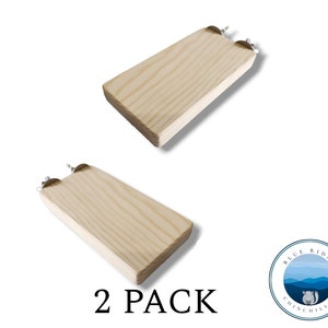 May include: Two wooden platforms with metal hooks for hanging in a cage. The platforms are light brown and have a natural wood grain. The text "2 PACK" is printed below the platforms.