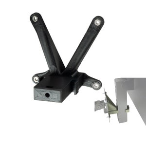 May include: A black plastic 3D printed bracket with a hole in the centre. The bracket has two arms that extend out at an angle. The bracket is designed to be mounted to a wall or other surface.