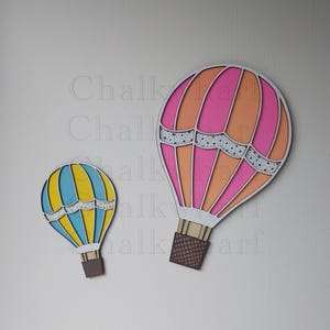 May include: Two wooden hot air balloons, one pink and orange with white polka dots and one blue and yellow with white polka dots.