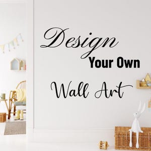 May include: A white wall featuring the text "Design Your Own Wall Art" in black script. A decorative bunny figurine sits on a woven basket. A small wooden toy and a shelf with decorative items are also visible.