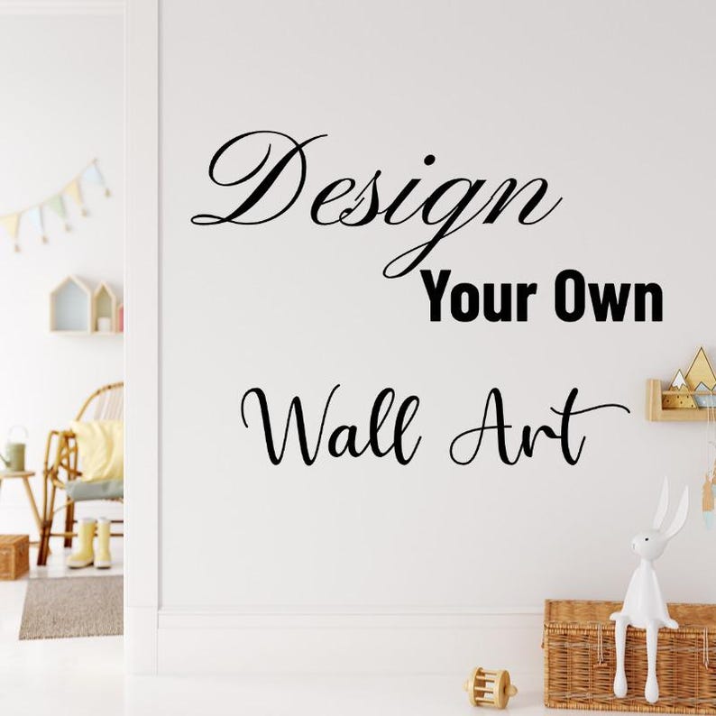 May include: A white wall featuring the text "Design Your Own Wall Art" in black script. A decorative bunny figurine sits on a woven basket. A small wooden toy and a shelf with decorative items are also visible.