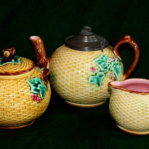 May include: A yellow and green tea set comprising a teapot, sugar bowl, and creamer. The set is decorated with a woven basket pattern and floral accents.
