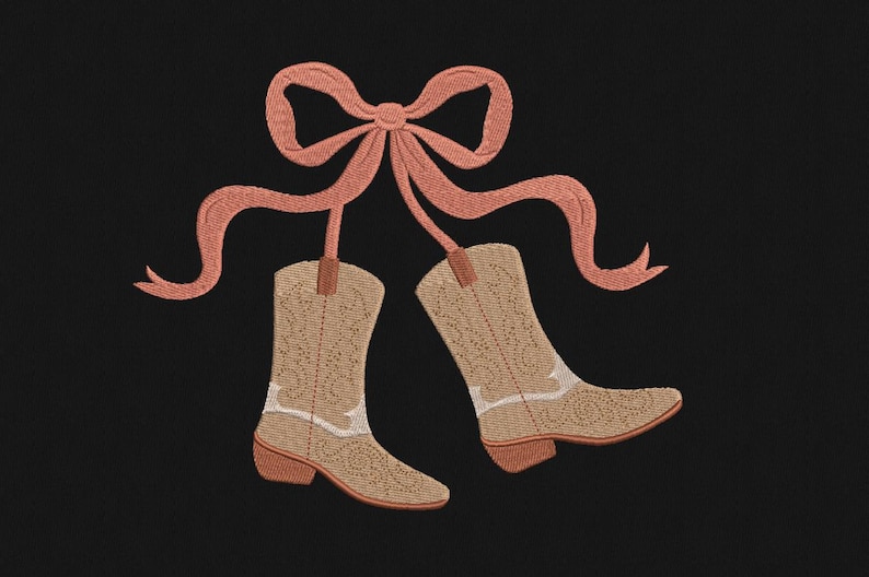 May include: Embroidered design of two cowboy boots hanging from a peach-colored bow on a black background. The boots are tan with white accents and a decorative pattern. The bow has long, flowing ribbons.