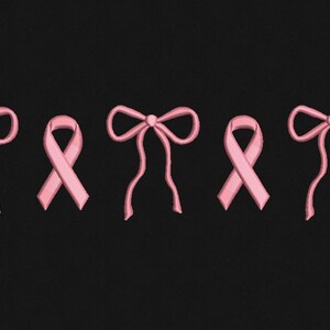 May include: Pink ribbon and bow embroidery on a black background. The design features three pink ribbons and two pink bows. The bows have long, flowing tails. The ribbons and bows are evenly spaced.