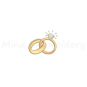 Puede incluir: Un diseño de bordado que presenta dos anillos dorados entrelazados, con el anillo de la derecha rematado por un diamante azul claro con líneas radiantes. El texto Mina Embroidery es visible en letras cursivas gris claro detrás de los anillos.