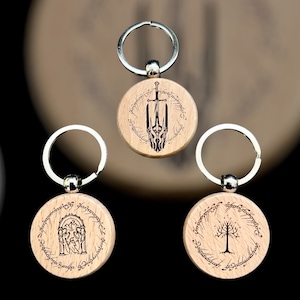 Peut inclure: Trois porte-clés en bois avec différents motifs du Seigneur des Anneaux. Le premier porte-clés représente l'inscription de l'Anneau Unique et une épée. Le deuxième porte-clés représente l'inscription de l'Anneau Unique et l'entrée des Mines de la Moria. Le troisième porte-clés représente l'inscription de l'Anneau Unique et l'Arbre Blanc de Gondor.