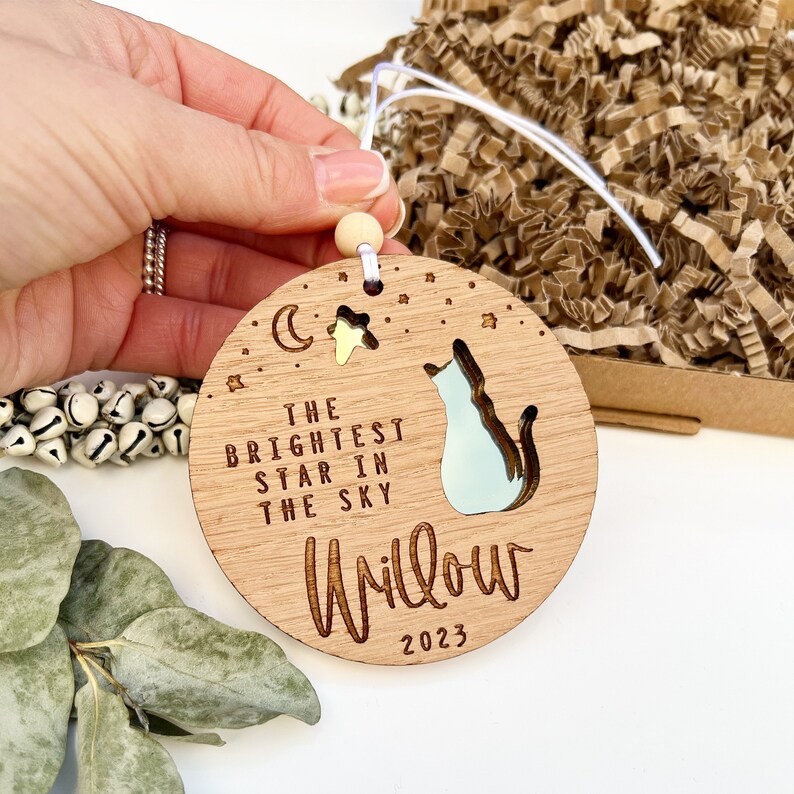 May include: A wooden ornament with a cat silhouette and the text "The brightest star in the sky Willow 2023".