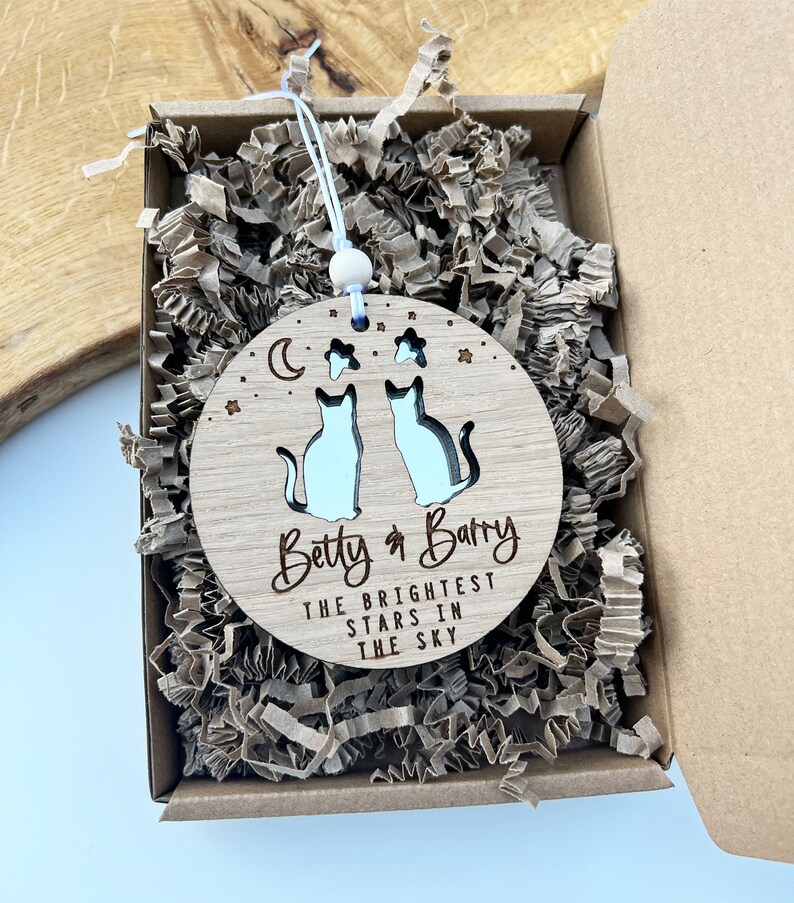 May include: A wooden ornament featuring two cats and stars, a crescent moon, and the text "Betty & Barry The Brightest Stars In The Sky".