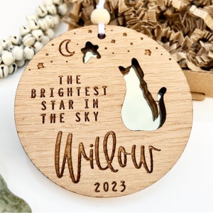 May include: A wooden ornament with a cat silhouette, a crescent moon, and a star. The text reads "The brightest star in the sky Willow 2023".