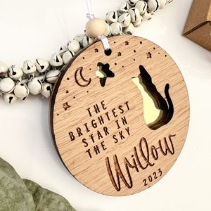 May include: Wooden ornament with a cat silhouette, a crescent moon, and a star. The text reads "The brightest star in the sky Willow 2023".