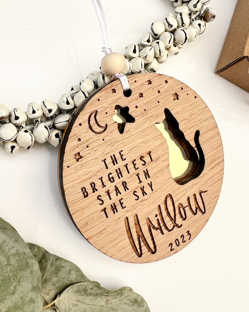 May include: Wooden ornament with a cat silhouette, a crescent moon, and a star. The text reads "The brightest star in the sky Willow 2023".