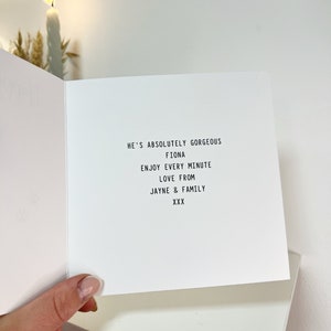 May include: A white card with black text that reads "He's absolutely gorgeous Fiona Enjoy every minute Love from Jayne & Family XXX"