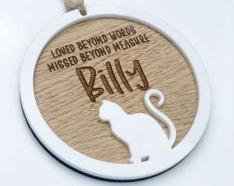 May include: A round wooden ornament with a white border, featuring a cat silhouette and the text "Loved beyond words, missed beyond measure, Billy".