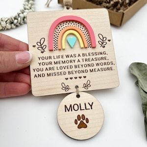 Può includere: Ciondolo commemorativo in legno con un design arcobaleno e il testo "YOUR LIFE WAS A BLESSING, YOUR MEMORY A TREASURE, YOU ARE LOVED BEYOND WORDS, AND MISSED BEYOND MEASURE." Un cerchio di legno più piccolo con il nome "MOLLY" e un'impronta di zampa è attaccato.