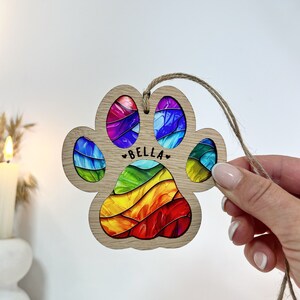 Peut inclure: Une d&eacute;coration de No&euml;l en bois en forme de patte d'animal avec un motif en spirale arc-en-ciel et le nom "BELLA" inscrit dessus. La d&eacute;coration est attach&eacute;e &agrave; une ficelle en ficelle.