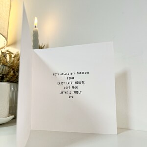 May include: A white card with black text that reads "He's absolutely gorgeous Fiona Enjoy every minute Love from Jayne & Family XXX"