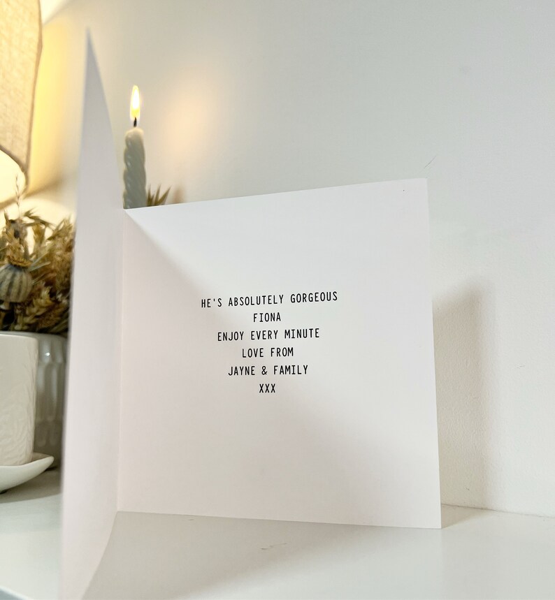 May include: A white card with black text that reads "He's absolutely gorgeous Fiona Enjoy every minute Love from Jayne & Family XXX"