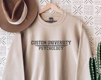 May include: A beige sweatshirt with the text "CUSTOM UNIVERSITY PSYCHOLOGY" printed on the front.