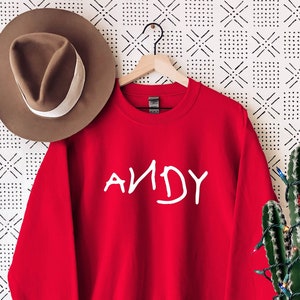Może przedstawiać: Czerwona bluza z napisem "ANDY" w kolorze białym z przodu.